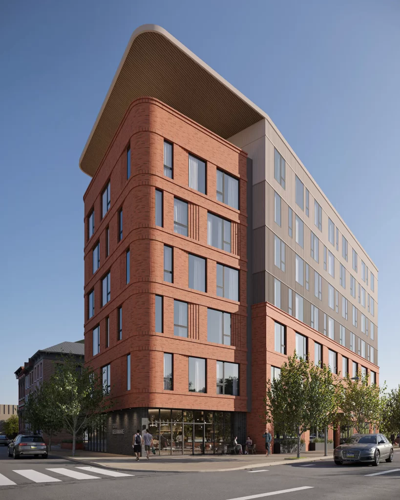 Immeuble mixte de moyenne hauteur à façade en brique rouge, toiture courbe et commerces en rez-de-chaussée